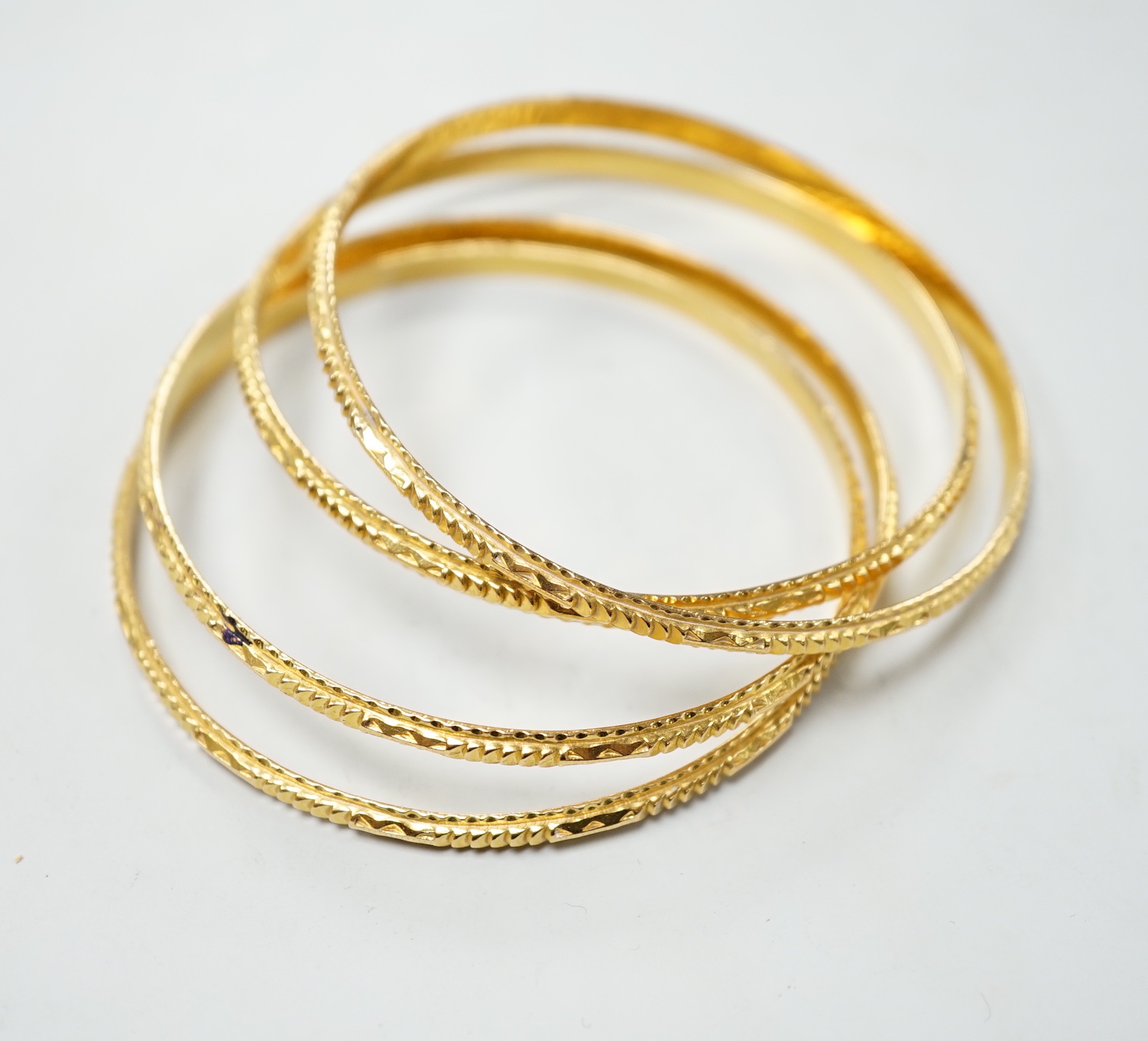 A set of four bright cut yellow metal bangles, 60 grams.